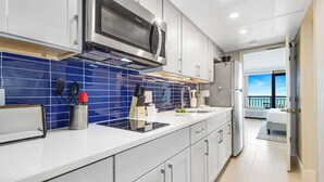 A modern kitchen with white cabinets, a blue backsplash, and stainless steel appliances. - Paradis By Casanita - Oceanfront Lux Designer Suite (Myrtle Beach)