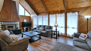 A cozy living room with a fireplace, a television, and a comfortable seating area. - Fully equipped Blue Mountain Chalet with outdoor hot tub (Town of the Blue Mountains)