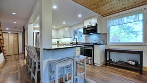 A modern kitchen with a central island, stainless steel appliances, and a wooden ceiling. - Fully equipped Blue Mountain Chalet with outdoor hot tub (Town of the Blue Mountains)