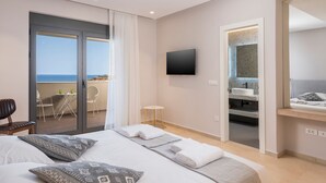 Ein modernes Hotelzimmer mit Bett, Fernseher, Badezimmer und einem Balkon mit Tisch und Stühlen.