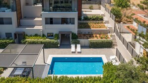 Ein modernes Wohngebäude mit Schwimmbad, mehreren Balkonen und einem gepflegten Garten.