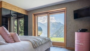 Ein Schlafzimmer mit einem Bett, einem großen Fenster, einem Fernseher und einer Chanel-Tasche im Barrelschnitt.