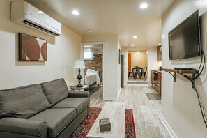 A modern living room with a grey sofa, a coffee table, and a TV mounted on the wall. - Staunton Underground: Center of Downtown (Staunton)