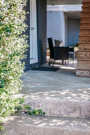 A concrete patio with a wooden bench and a table, surrounded by greenery. - Staunton Underground: Center of Downtown (Staunton)