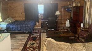 A cozy room with a bed, a desk, a chair, and a sofa. There is a window with curtains and a ceiling fan. - Cozy Studio apartment with cabin feel (Tallahassee)