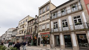 A street with buildings featuring storefronts, including a visible sign for 'NOVALMA'. - Capela 2 in Oporto With 1 Bathrooms (Porto)