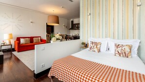 A hotel room with a large bed, a red sofa, a kitchen area, and a striped wall. - Torre 1 in Oporto With 1 Bathrooms (Porto)