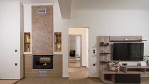 A modern living room with a fireplace, wooden flooring, and built-in shelving. - Villa Cataleya : A Spacious, Private Oasis with a Pool Near the Beach (Chania)