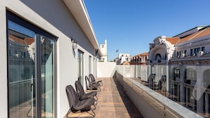 A balcony with wicker chairs, a wooden floor, and a view of historic buildings. - RA - Santa Catarina in Oporto (Porto)