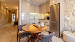 A modern kitchen with a central island, stainless steel appliances, and a stone accent wall. - Ribeira Gaia 2 in Vila Nova de Gaia (Vila Nova de Gaia)