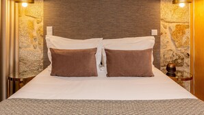 A neatly made bed with two pillows, a textured wall, and two wall-mounted lights. - Ribeira Gaia 2 in Vila Nova de Gaia (Vila Nova de Gaia)