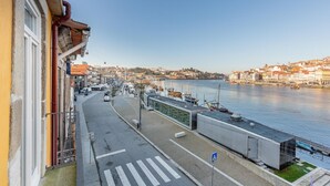 A waterfront view from a balcony overlooking a cityscape with buildings, a clear sky, and a calm river. - Ribeira Gaia 2 in Vila Nova de Gaia (Vila Nova de Gaia)
