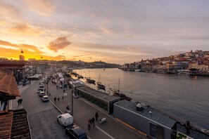 A waterfront cityscape with a row of buildings along the river, a pedestrian walkway, and parked cars. - Ribeira Gaia 3 in Vila Nova de Gaia (Vila Nova de Gaia)