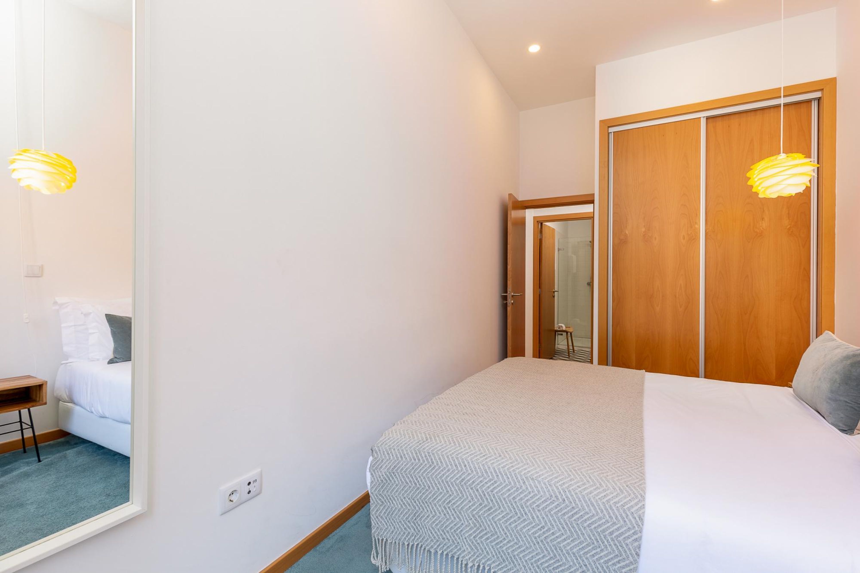 Ein Schlafzimmer mit einem Bett, einem Holzschrank, einem Spiegel und einem kleinen Tisch.