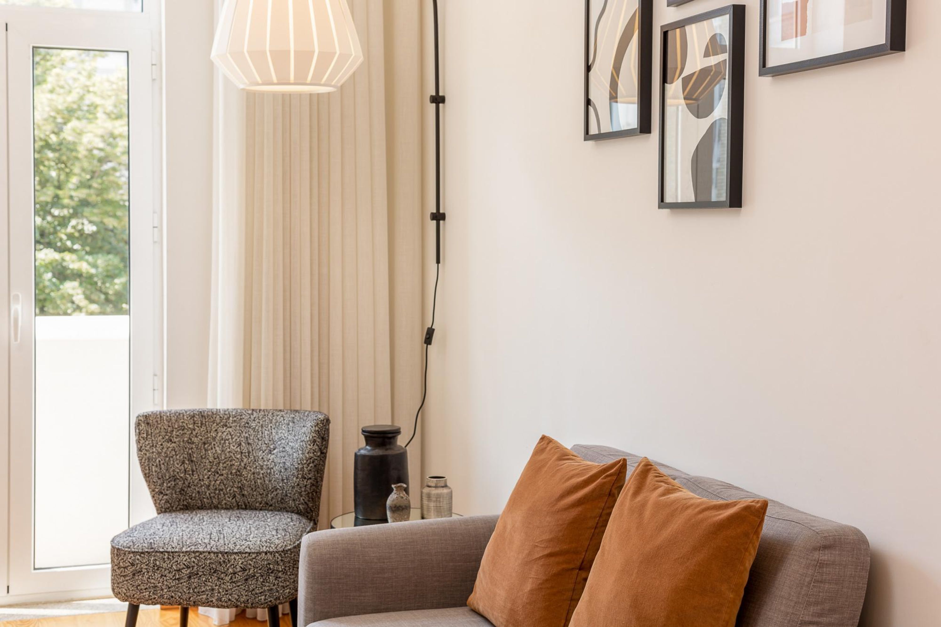 A modern living room with a grey sofa, a patterned armchair, and a floor lamp.