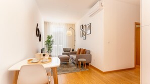A modern living room with a sofa, armchair, and dining table with chairs. - Cosy 5 in Oporto With 1 Bedrooms and 1 Bathrooms (Porto)