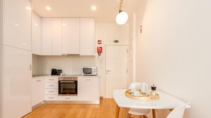 A modern kitchen with white cabinets, a microwave, and a coffee machine. There is a dining table with a tray of cups and a teapot. - Cosy 5 in Oporto With 1 Bedrooms and 1 Bathrooms (Porto)