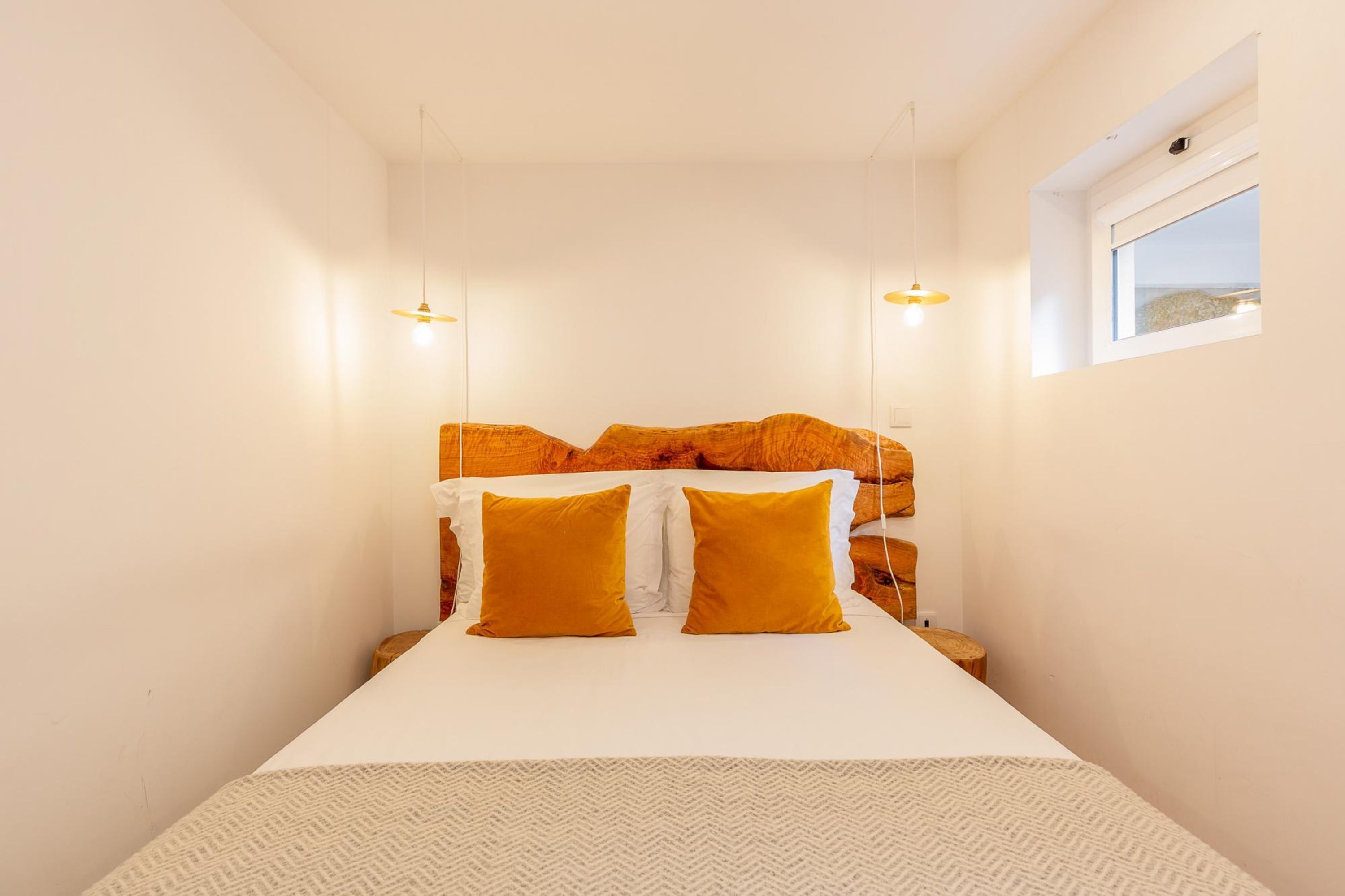 Une chambre à coucher comprenant un lit, deux lampes de chevet, une fenêtre et une tête de lit au design original.