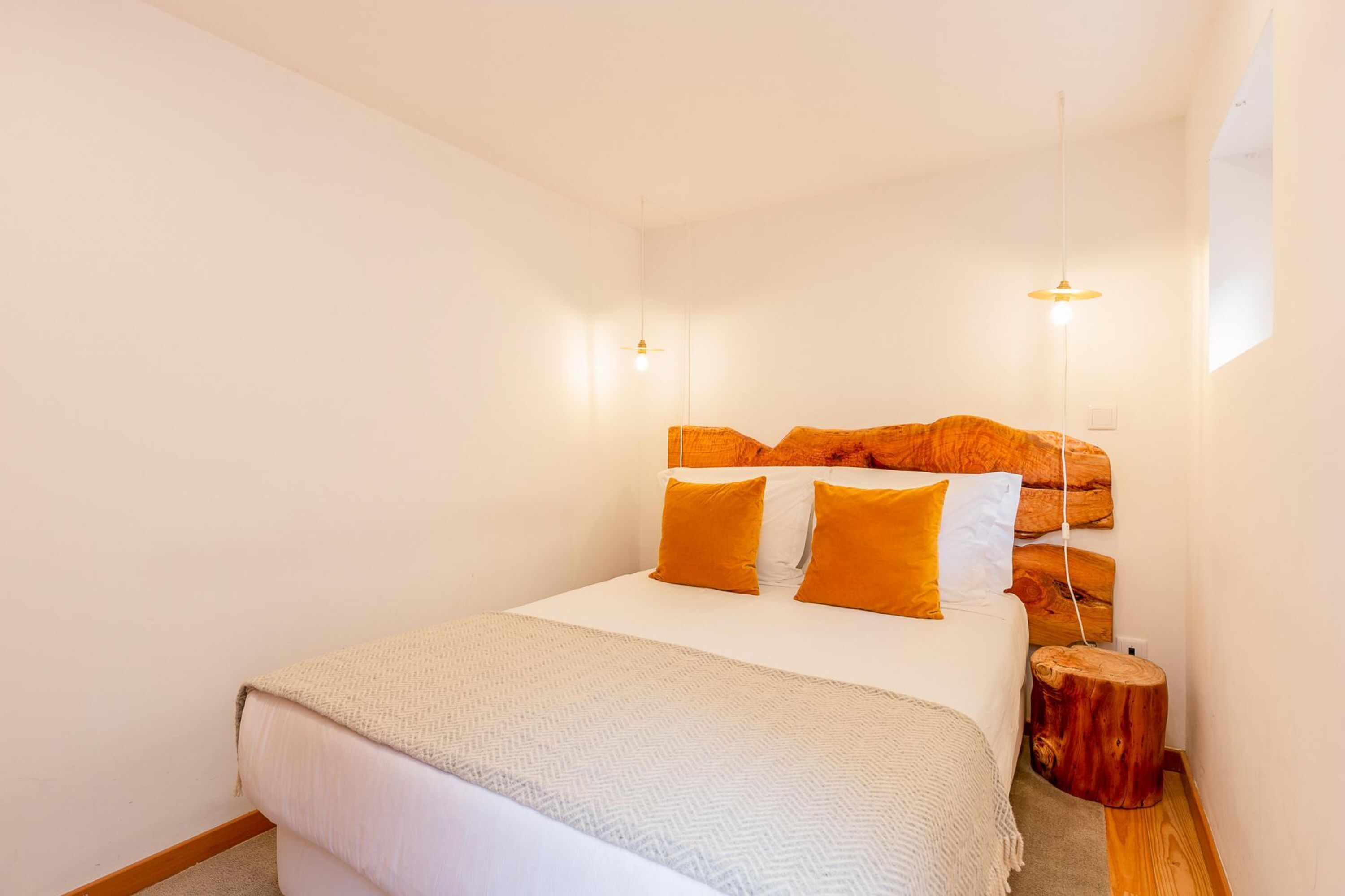Un dormitorio con cama, paredes blancas y cabecera de madera.