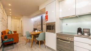 A modern kitchen with white cabinets, a built-in microwave, and a coffee machine. There is a dining area with a wooden table and chairs. - Ribeira Porto 0 in Oporto (Porto)