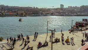 A waterfront promenade with people walking, benches, and a view of the water with boats. - Ribeira Porto 1 in Oporto (Porto)