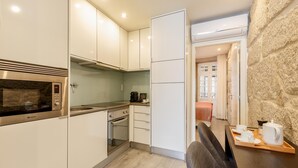 A modern kitchen with stainless steel appliances, white cabinetry, and a wooden dining table set for two. - Ribeira Porto 1 in Oporto (Porto)