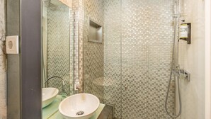 Une salle de bain avec une douche à parois de verre, un lavabo avec un miroir et des murs carrelés.
