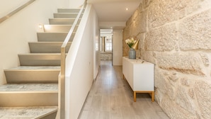 A modern staircase with a stone wall on one side and a white console table with a vase on the other. - Ribeira Porto 3 in Oporto (Porto)