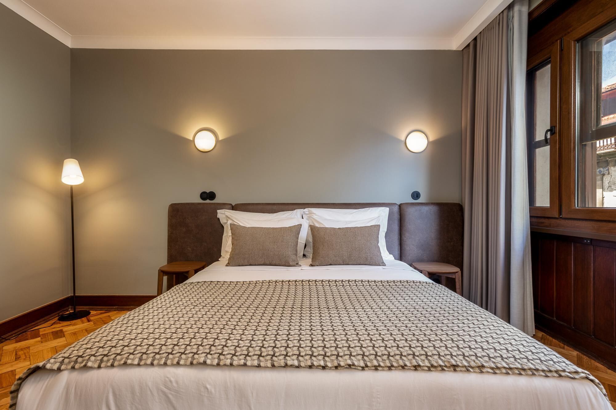 Een hotelkamer met een groot bed, twee nachtkastjes, een hoofdeinde en twee wandlampen.