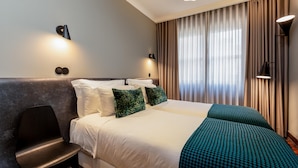 Quarto de hotel com uma cama grande, duas almofadas, uma cadeira e uma escrivaninha.