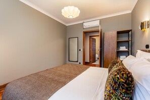 Une chambre à coucher comprenant un lit, une armoire, un miroir et une porte donnant accès à une salle de bain.