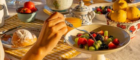 Una mesa de desayuno con croissants, naranjas y un bol de fruta.