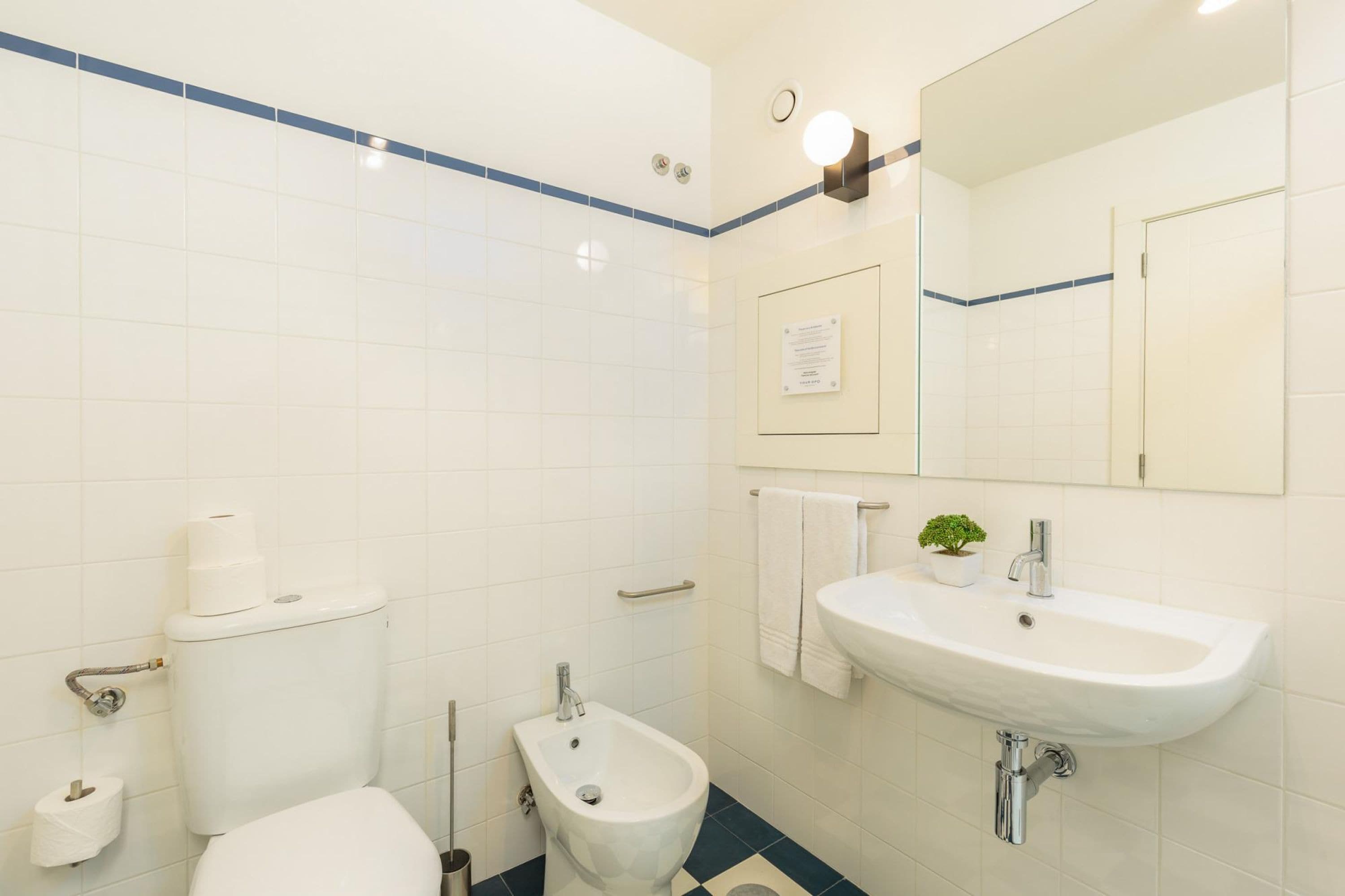Une salle de bain comprenant des toilettes, un bidet, un lavabo et un miroir.