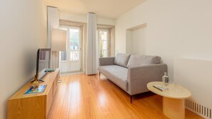 A modern living room with a grey sofa, a wooden coffee table, and a TV on a wooden stand. - Flores M in Porto With 1 Bedrooms and 1 Bathrooms (Porto)