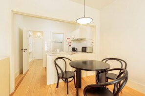 A compact kitchen with a dining area, featuring a round table and four chairs, a hanging light fixture, and a microwave. - Flores G in Porto With 1 Bedrooms and 1 Bathrooms (Porto)