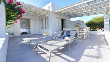Relax in a serene patio area with a pergola, lounge chairs, and a table, complemented by a fireplace.
