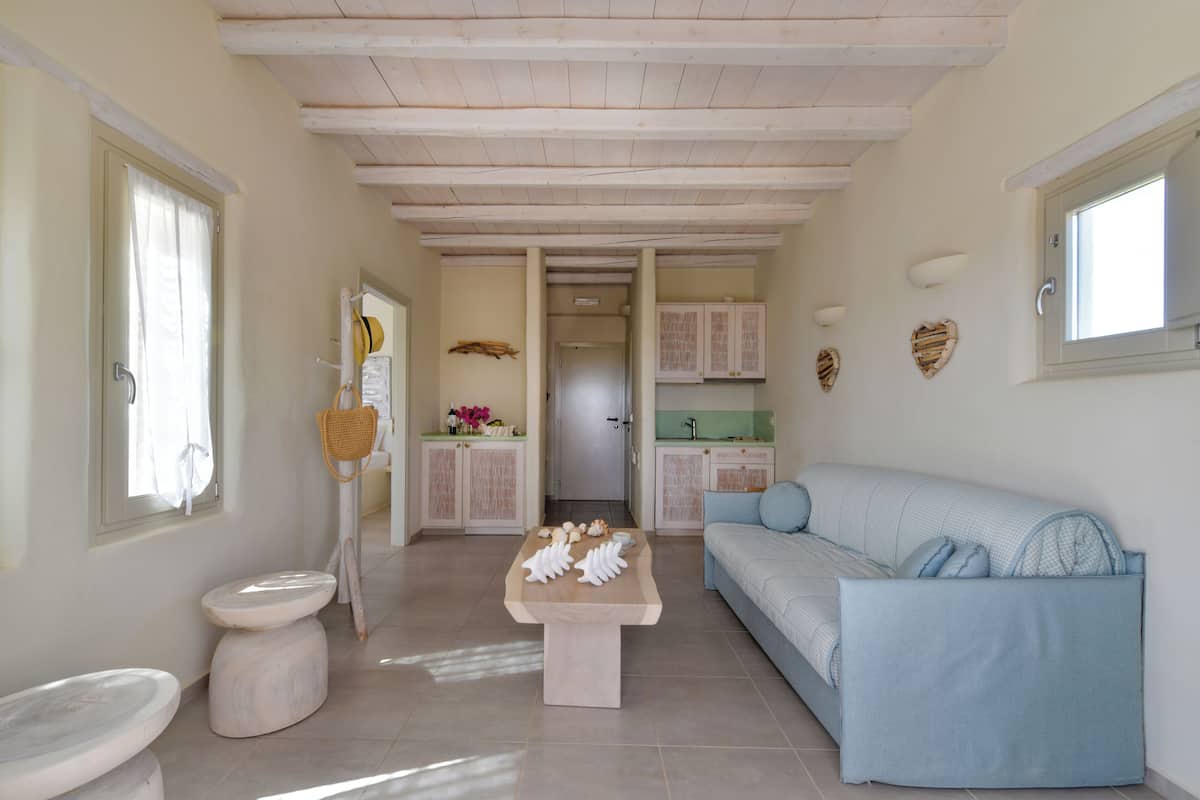 A spacious living area with a light blue sofa, a wooden coffee table, and a white cabinet.