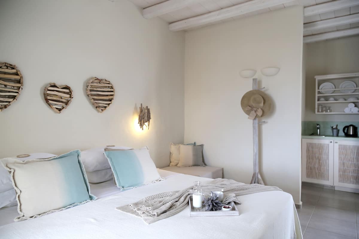 A bedroom with a bed, pillows, a bedside table, a tray with items, and a wall with decorative objects.