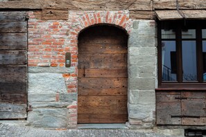 A rustic wooden door with a brick archway, set in a stone wall. - Domus Acaja-Elegant Apartment in the Historic Center-Fully Equipped Kitchen (Pinerolo)