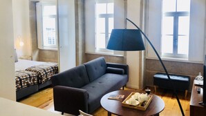 A modern room with a sofa, a small round table with teapots, and a floor lamp. - Tower 5F in Oporto With 1 Bathrooms (Porto)