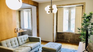 Ein modernes Wohnzimmer mit einer Couch, einem Hocker und einer Topfpflanze.