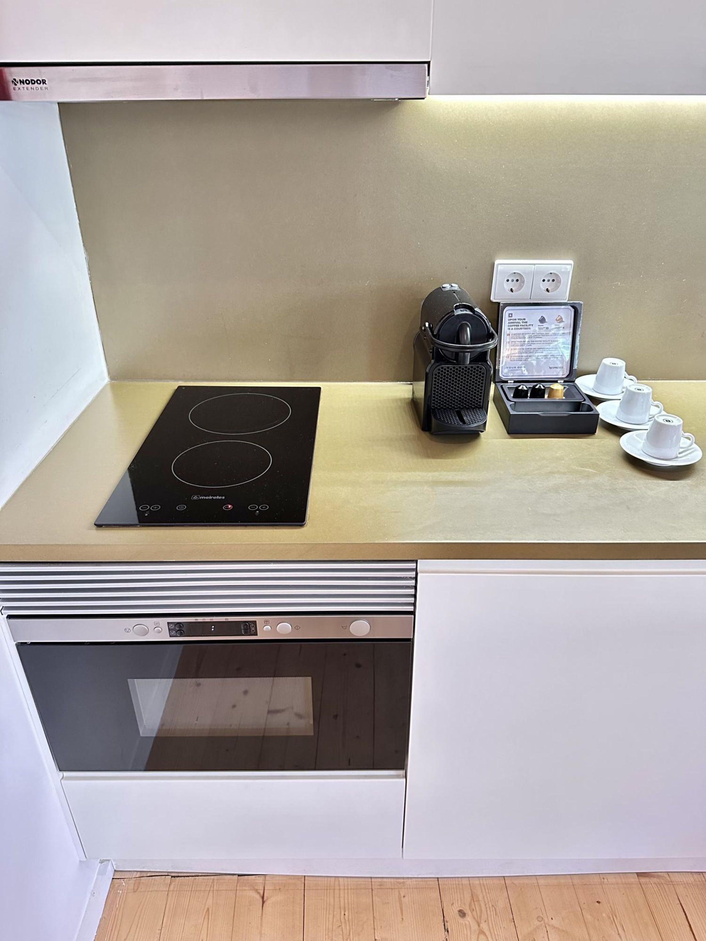 Une cuisine compacte équipée d’une cuisinière intégrée, d’une machine à café et d’un service à thé.