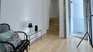 Una habitación amplia con una cama, una mesita con lámpara y una escalera que lleva a un balcón.