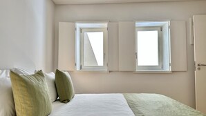 Un dormitorio con una cama, dos ventanas y una puerta.