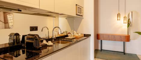 A modern kitchen with a black countertop, stainless steel appliances, and a wooden sideboard.