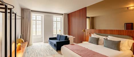 A hotel room with a large bed, a desk, a chair, and a view of the outside.