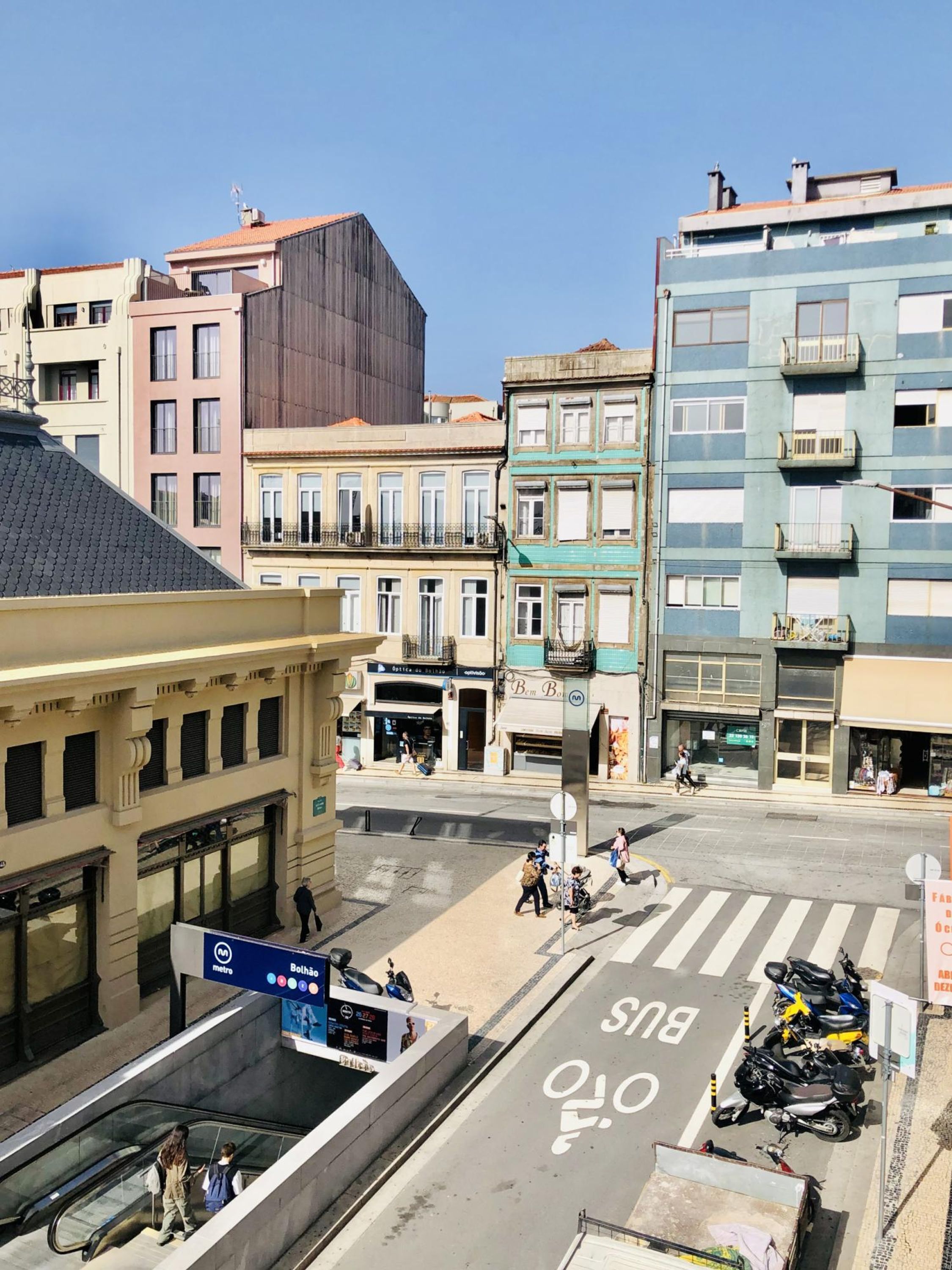 A street view with a metro sign, a crosswalk, and a mix of residential and commercial buildings.