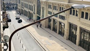 A street view with a building featuring a large arched entrance and a dome. - Downtown 2A in Oporto (Porto)