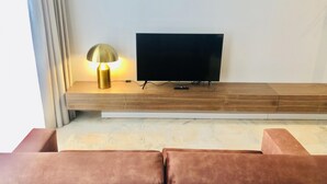 A modern living room with a flat-screen TV mounted on a wooden console, a floor lamp, and a pair of brown sofas. - Downtown 3C in Oporto (Porto)
