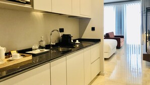 A modern kitchen with a built-in microwave, a sink, and a coffee maker. There is a bed with a view of the outdoors in the background. - Downtown 3C in Oporto (Porto)